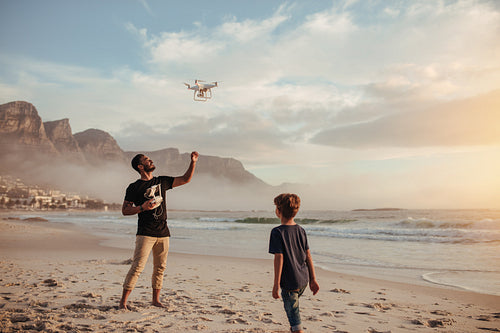 Father and son operating drone by remote control at beach