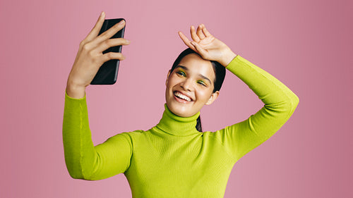 Taking glamour selfies in the studio, young generation z woman posing for a camera phone