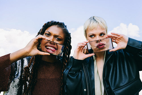 Women make funny faces with a smartphone outdoors