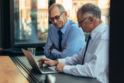 Senior businessmen working on a laptop at cafe counter