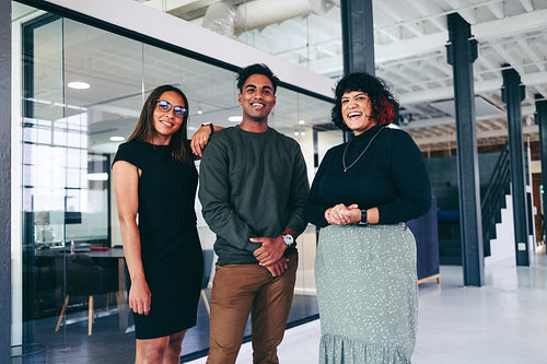 Colleagues smiling cheerfully while standing together in an office