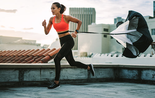 Fitness woman training with a resistance parachute on rooftop