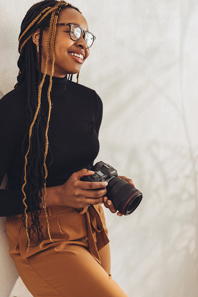 Young photographer standing against a wall