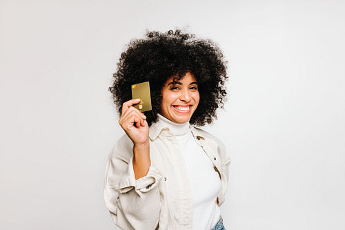 Cheerful young woman smiling at the camera while holding a credit card