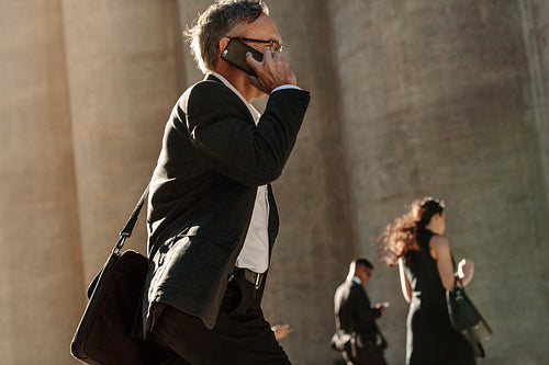 People using mobile phone while walking on street to office