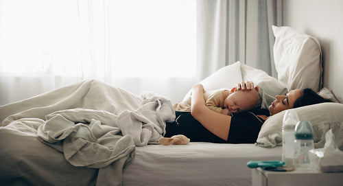 Mother cuddling baby in bed