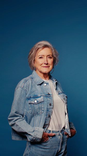 Confident senior woman in denim smiles for studio portrait on blue background