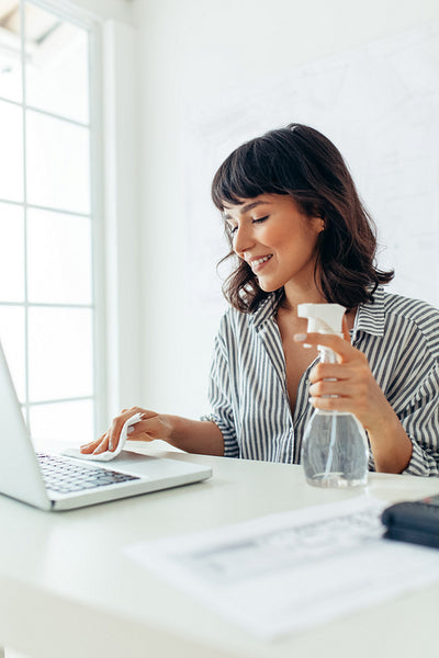 Businesswoman cleaning her laptop with sanitizer