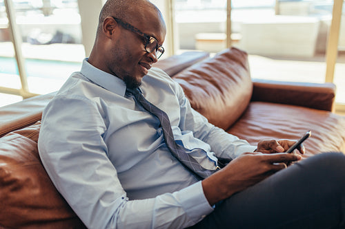 Businessman sitting on lounge using mobile phone