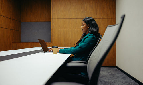 Professional Indian woman working on laptop in modern office setting