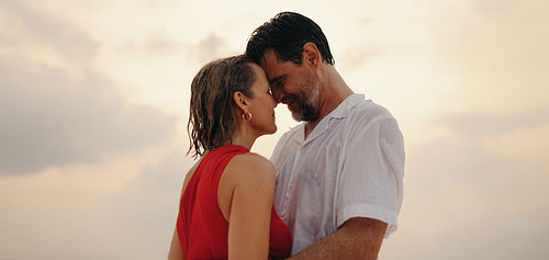 Mature newlyweds embracing at sunset by the beach after a swim, experiencing love and connection
