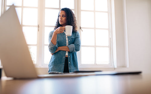 Businesswoman standing in office drinking coffee