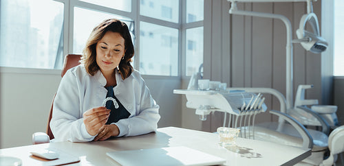 Female dentist examines aligner at clinic desk for patient consultation