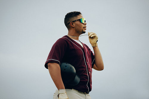 Pre-game ritual: Baseball player with helmet holds necklace a cloudy day