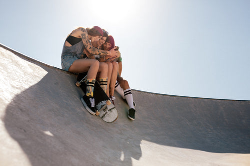 Women skaters using mobile phone at skate park
