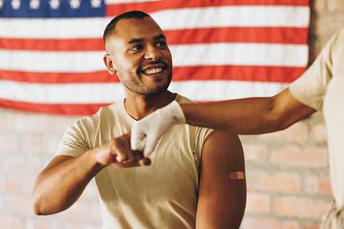 Cheerful young soldier fist bumping a medic after getting vaccin
