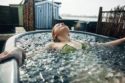 Woman relaxes in an outdoor ice bath for cold recovery
