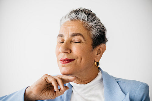 Silver-haired business woman sitting in her office with closed eyes