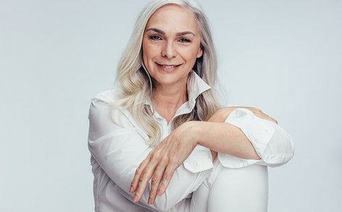 Beautiful mature woman sitting over white background