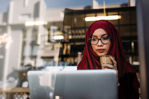 Hijab girl with coffee using laptop at cafe