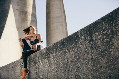 Sporty woman sitting outdoors after fitness training