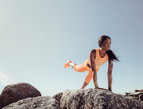 Female doing stretching exercises on beach rocks