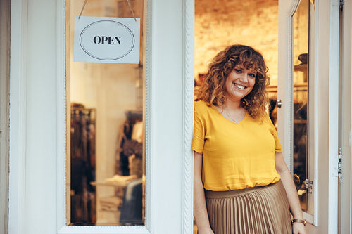 Businesswoman leaning to the doorway of her fashion store
