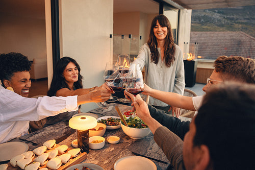 Friends toasting wine glasses at a cozy dinner on a patio