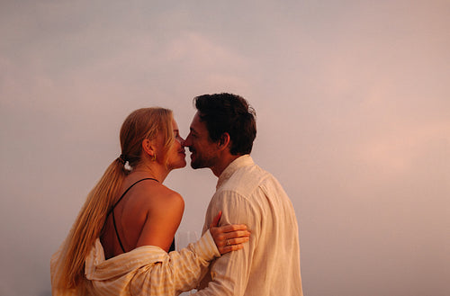 Sunset romance: Couple sharing a holiday kiss