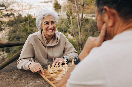 Retired couple enjoying a game of chess in a park