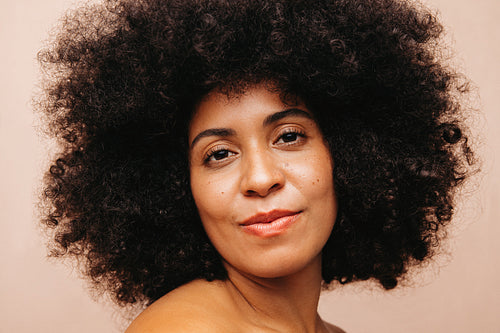 Confident woman with Afro hair looking at the camera in a studio