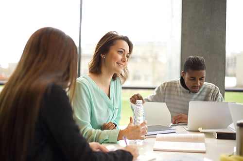Young woman studying in the library with other students