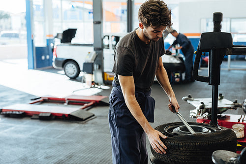 Mechanic changing car tire in service station