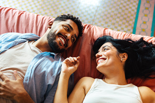 Couple sharing a cheerful moment together lying on a colorful bedspread