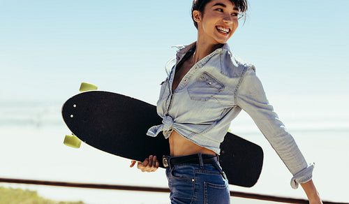 Woman walking outdoor on summer day with a skateboard