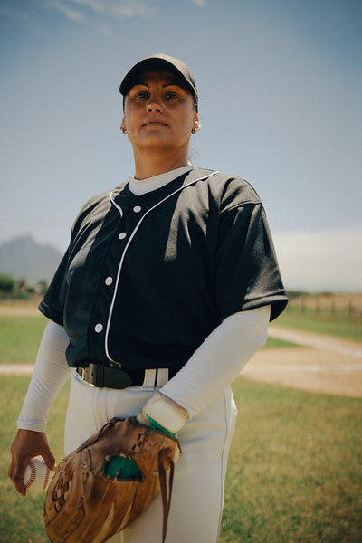 Confident female baseball pitcher standing on the field ready to throw a pitch
