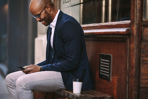 Businessman using smart phone sitting outside