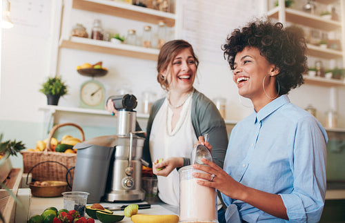 Happy young women working at juice bar counter
