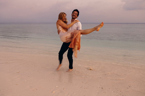 Newlyweds enjoying a joyful moment on an island beach at sunset