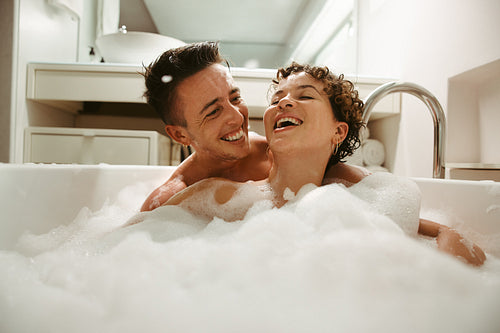 Cheerful queer couple enjoying bathing together at home