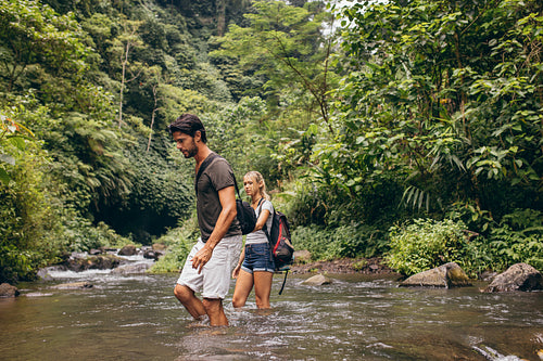 Couple crossing mountain stream