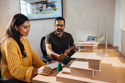 Two architects collaborating on a project with a scale model of a building