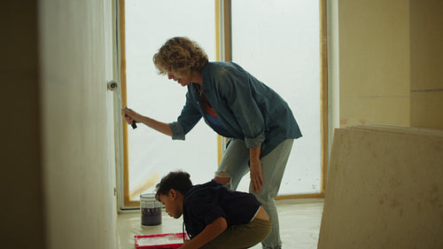 Mother and son painting wall during home renovation