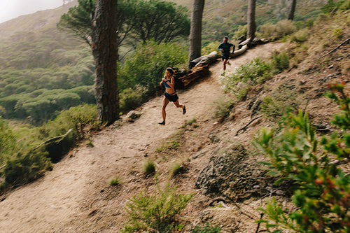 Young couple trail running on a mountain path.