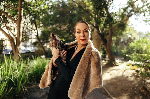 Carefree posh woman looking at the camera while holding her puppy