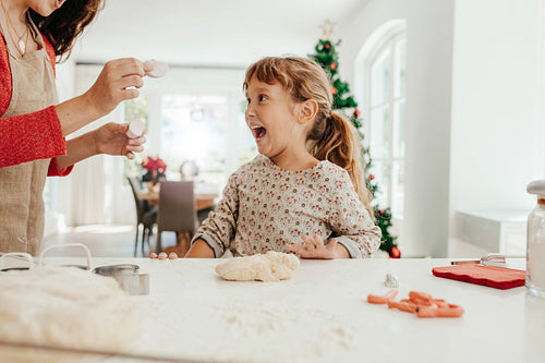 Mother and daughter in kitchen making cookies for Christmas.