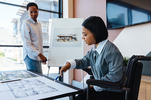 Two women discussing architectural plans in a modern office setting