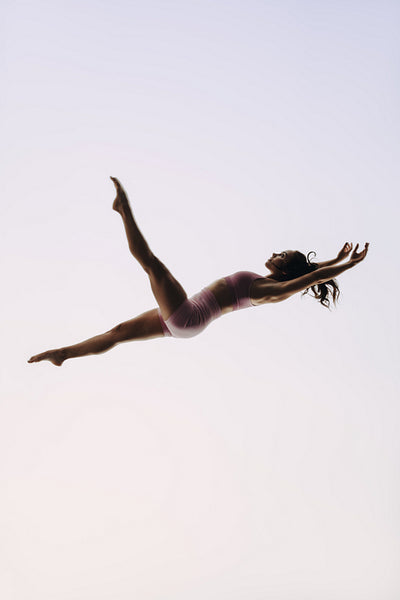 Female acrobat in athletic sportswear exhibiting agile skill in a mid air performance