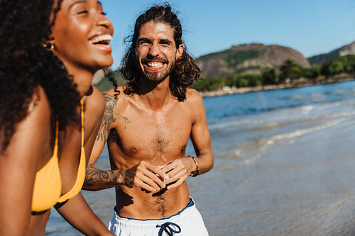 Joyful couple enjoying a sunny day at Praia do Flamengo beach with scenic views of the ocean and nature