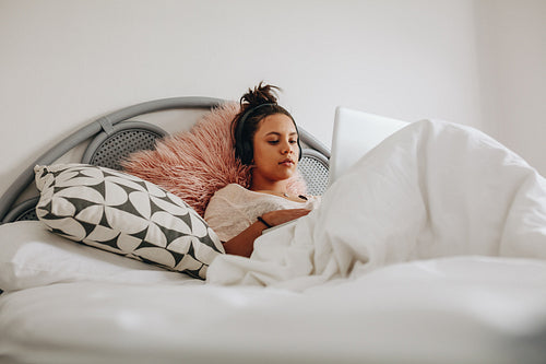 Girl working on laptop lying on bed